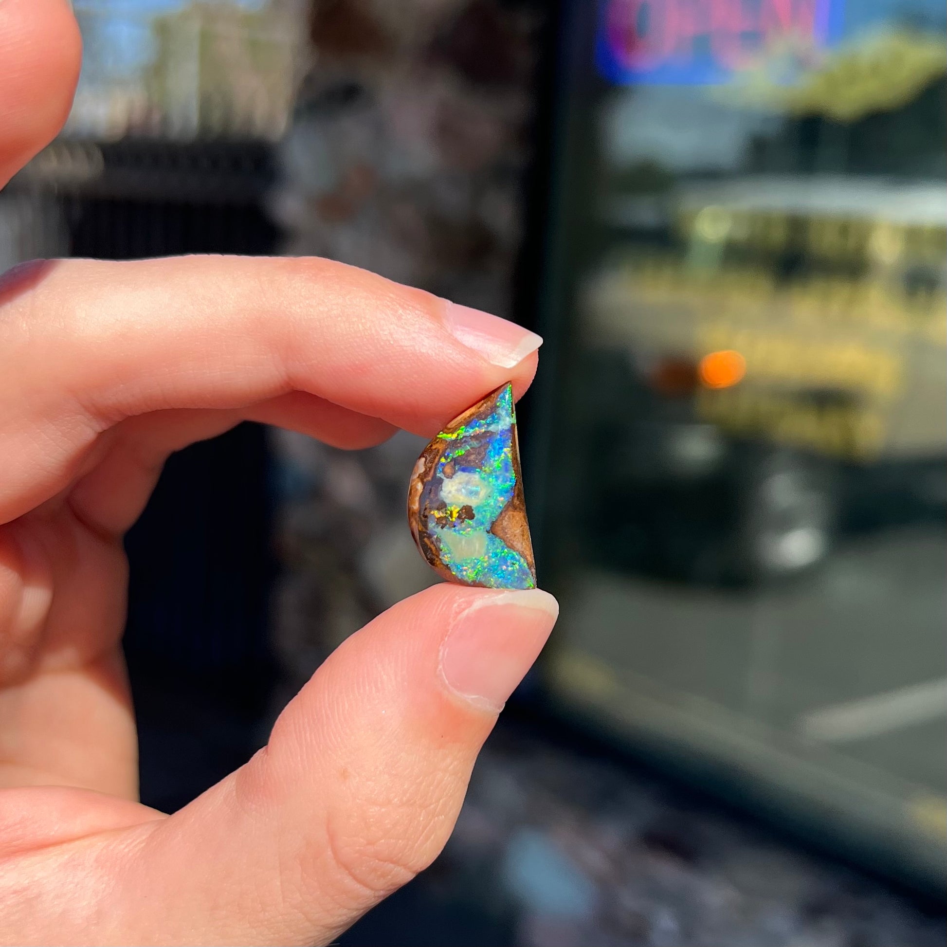 A loose, freeform shaped boulder opal with green and blue multicolor fire from Australia.