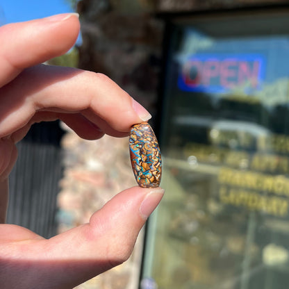 A loose, barrel shaped Koroit boulder opal stone with blue veins.