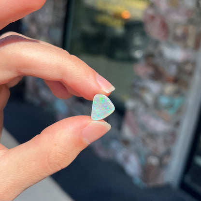 A freeform shaped blue-green light opal stone from Lightning Ridge, Australia.