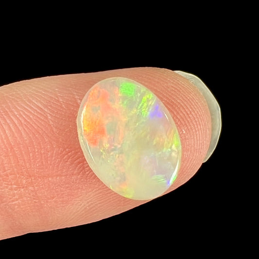 An oval cut opal with red, green, and blue fire from Coober Pedy, Australia.