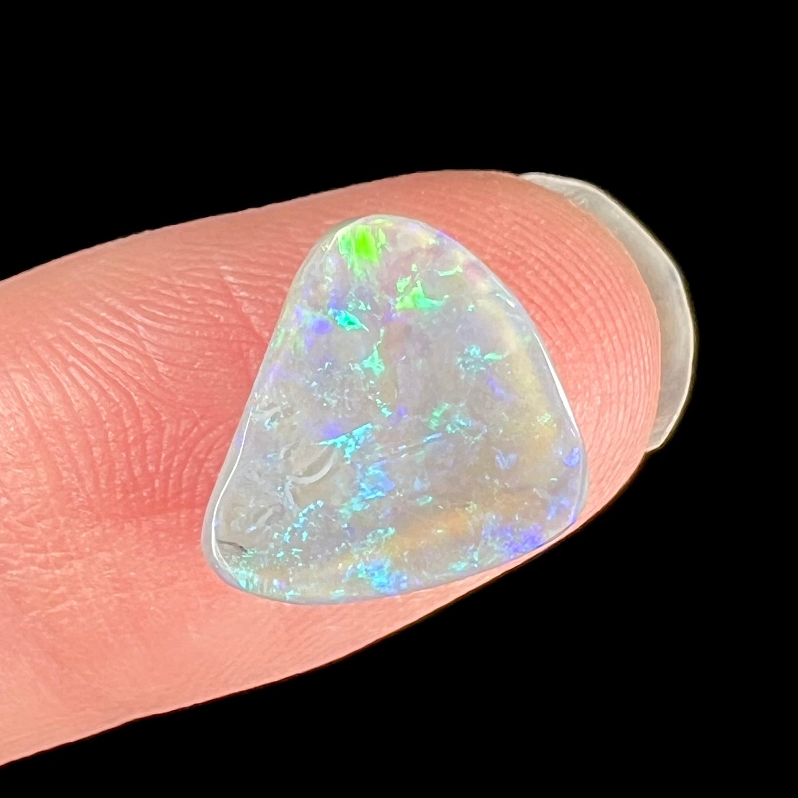 A freeform shaped blue-green light opal stone from Lightning Ridge, Australia.