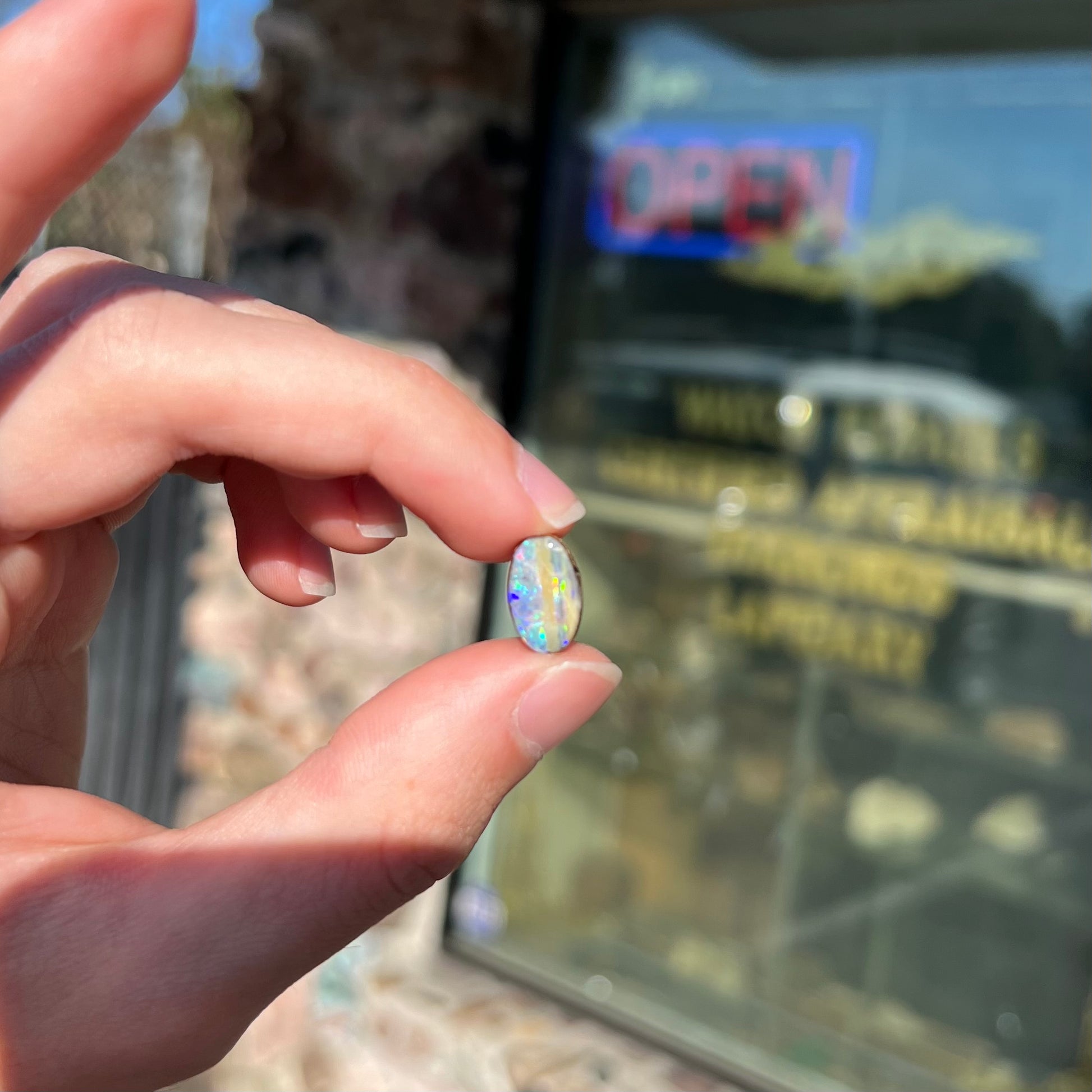 An oval cabochon cut boulder opal from Quilpie, Australia.  The opal has multicolor color play.