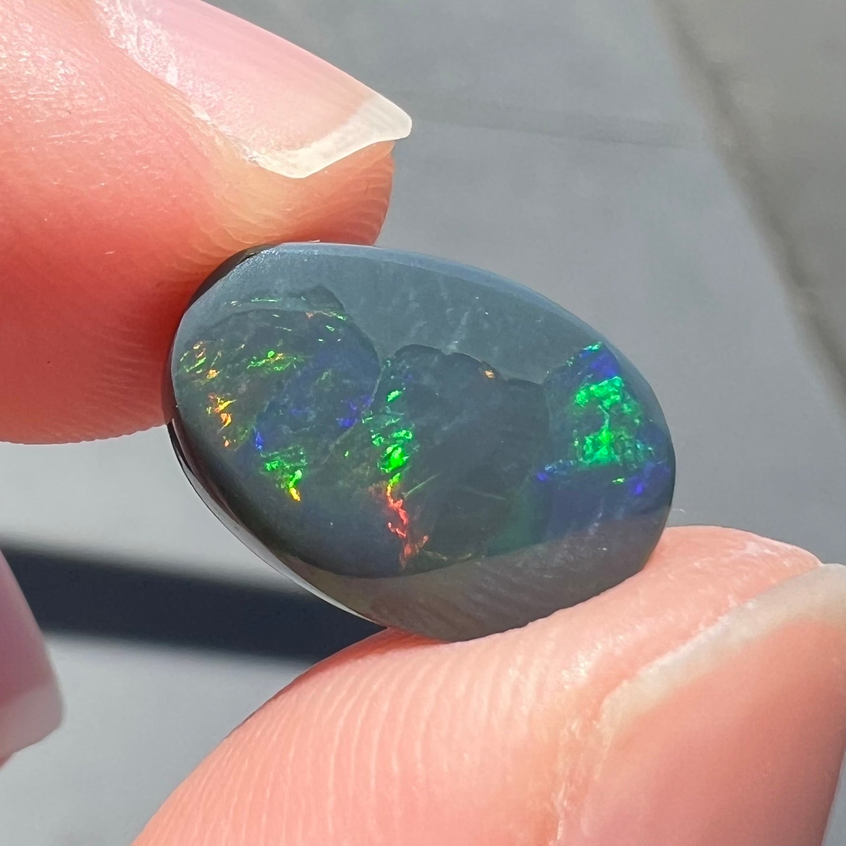 A loose, freeform cut black opal stone from Lightning Ridge, Australia.