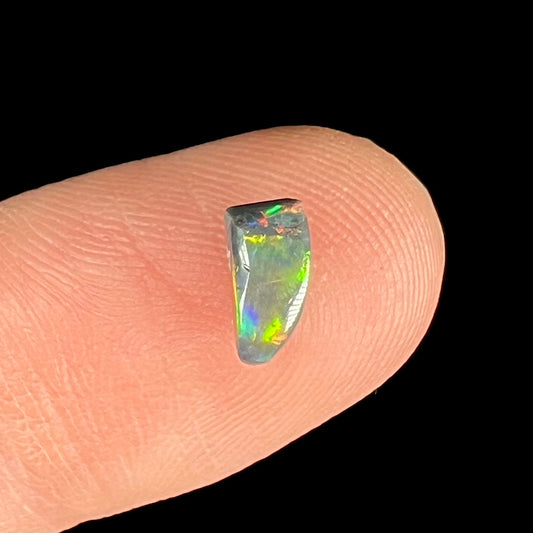 A freeform shaped black opal stone from Lightning Ridge, Australia.