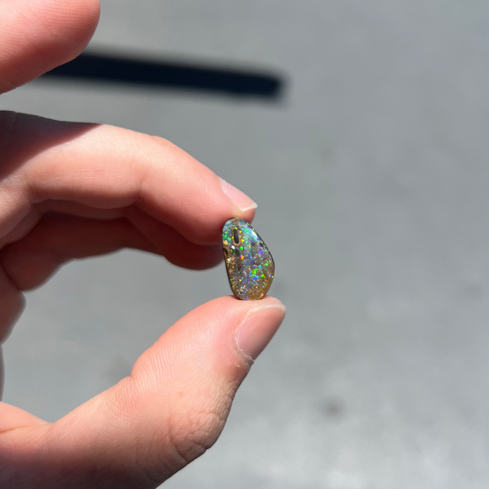 A loose boulder opal stone from Quilpie, Australia.  The opal shines colors of green and orange.