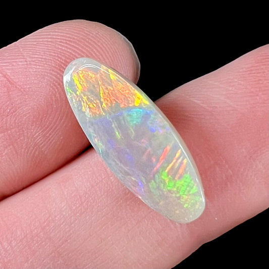 A loose, oval cabochon cut opal stone from Coober Pedy, Australia.