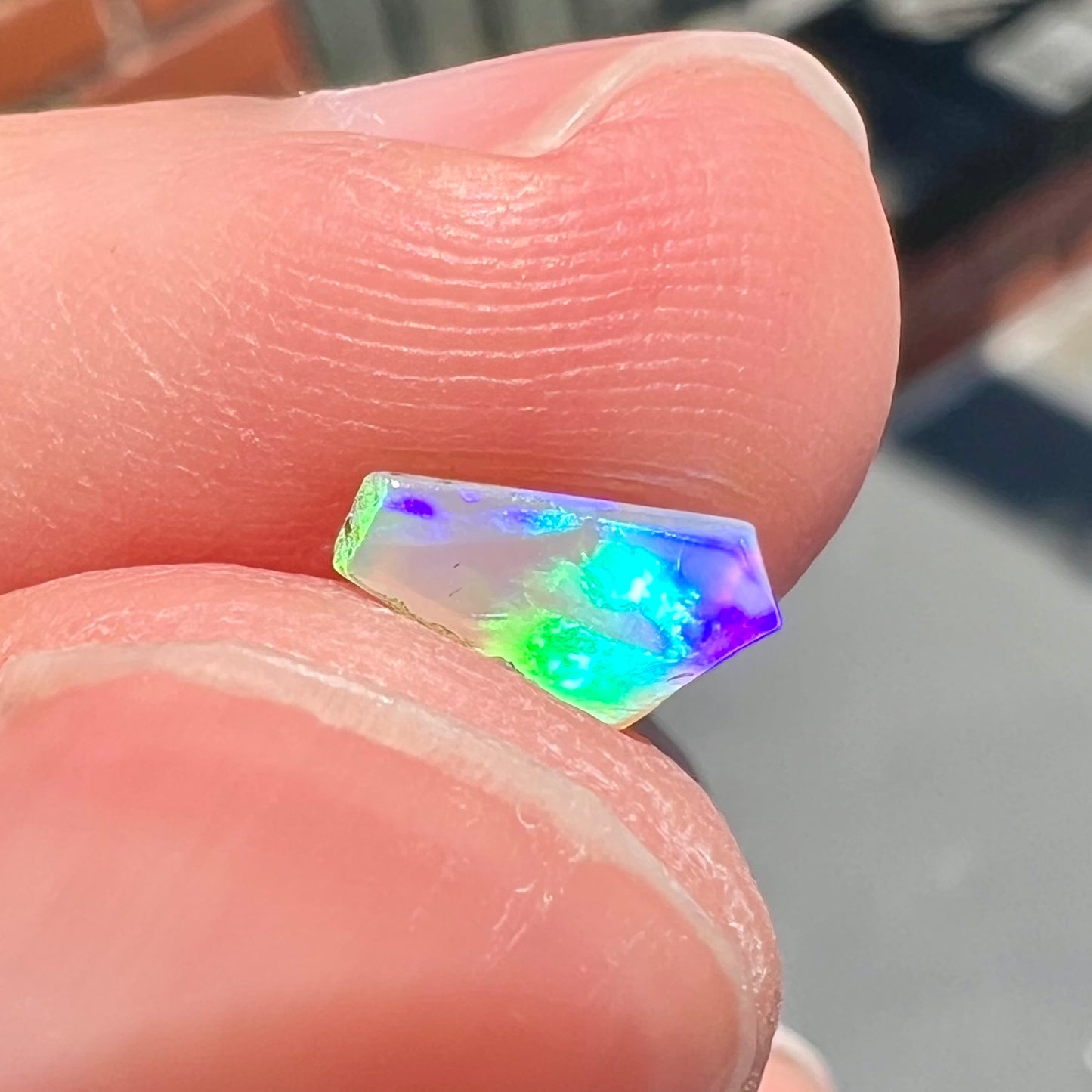 A loose, Australian fire opal chip.  The stone shines red, green, and yellow colors.