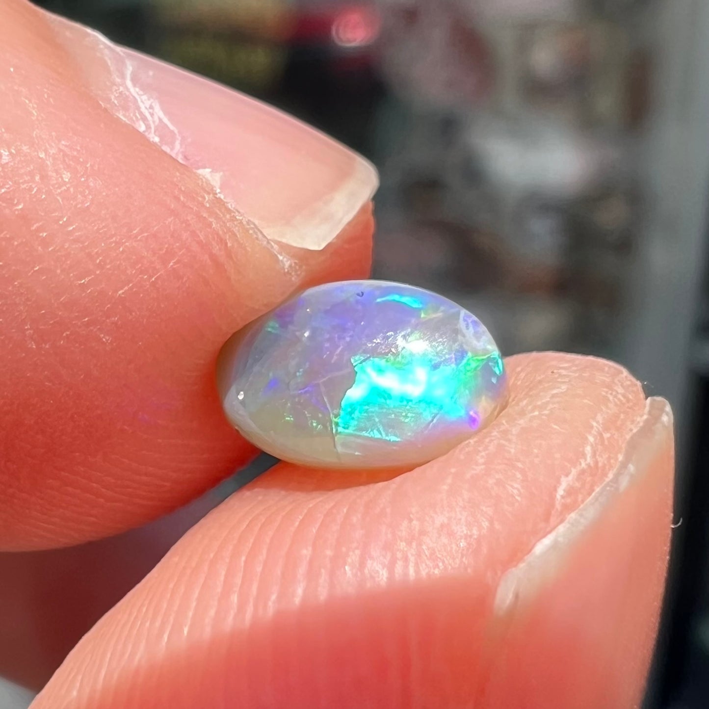 A loose, oval cabochon cut semi-black crystal opal from Lightning Ridge, Australia.