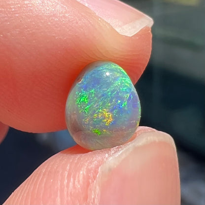 A loose, freeform shaped semi-black opal stone from Lightning Ridge, Australia.