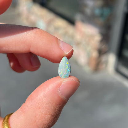 A loose, pear shaped Australian opal stone.  The opal shows green and blue colors.