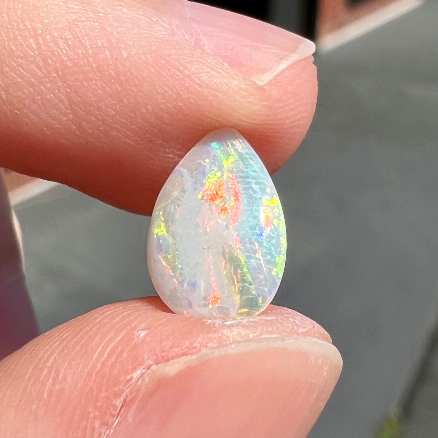 A loose, pear shaped Australian white opal stone.  The stone plays every color of the rainbow.