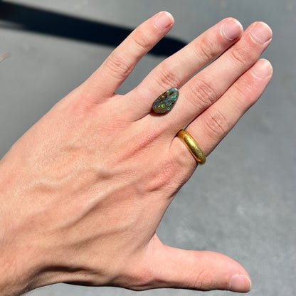 A loose boulder opal stone from Quilpie, Australia.  The opal shines colors of green and orange.