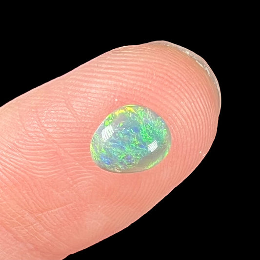 A loose, freeform shaped semi-black opal stone from Lightning Ridge, Australia.