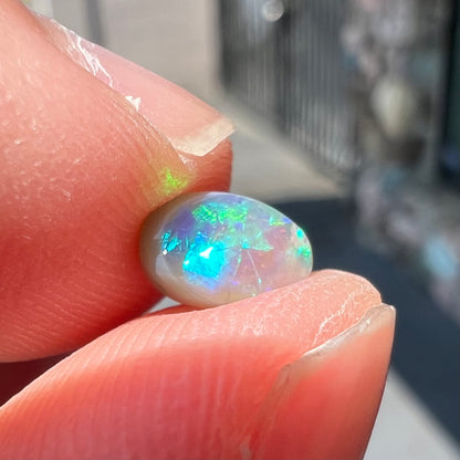 A loose, oval cabochon cut semi-black crystal opal from Lightning Ridge, Australia.