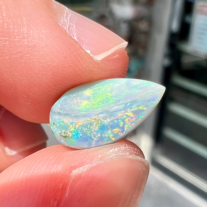 A loose, pear shaped Australian opal stone.  The opal shows green and blue colors.