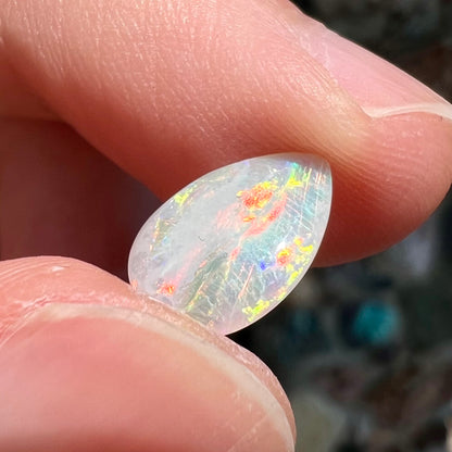 A loose, pear shaped Australian white opal stone.  The stone plays every color of the rainbow.