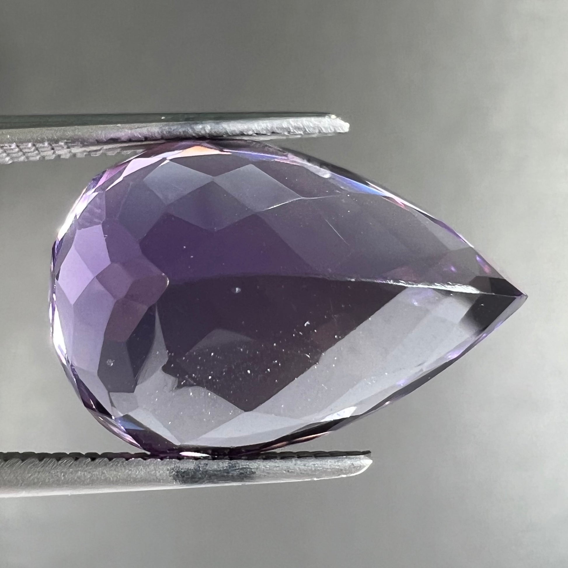 A loose, pear shaped amethyst gemstone.  The stone is a medium purple color.