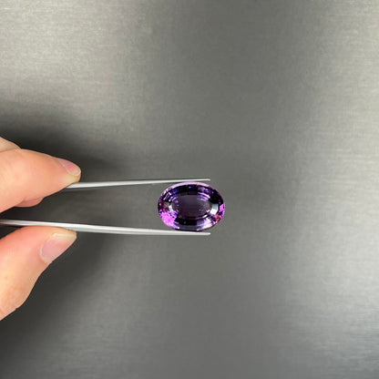 A loose, modified oval step cut amethyst gemstone.  There are light scratches to the table.