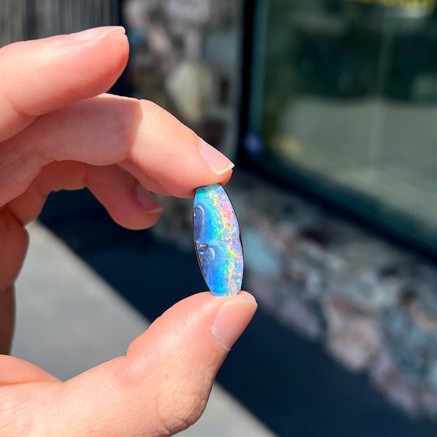 A barrel shaped boulder opal gemstone with a rainbow of colors.