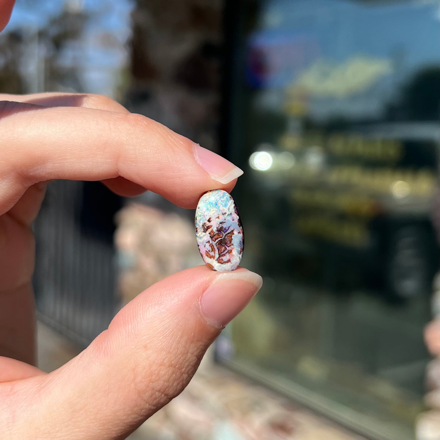 An oval cabochon cut boulder opal stone from Koroit, Australia.  The opal has a white body tone.