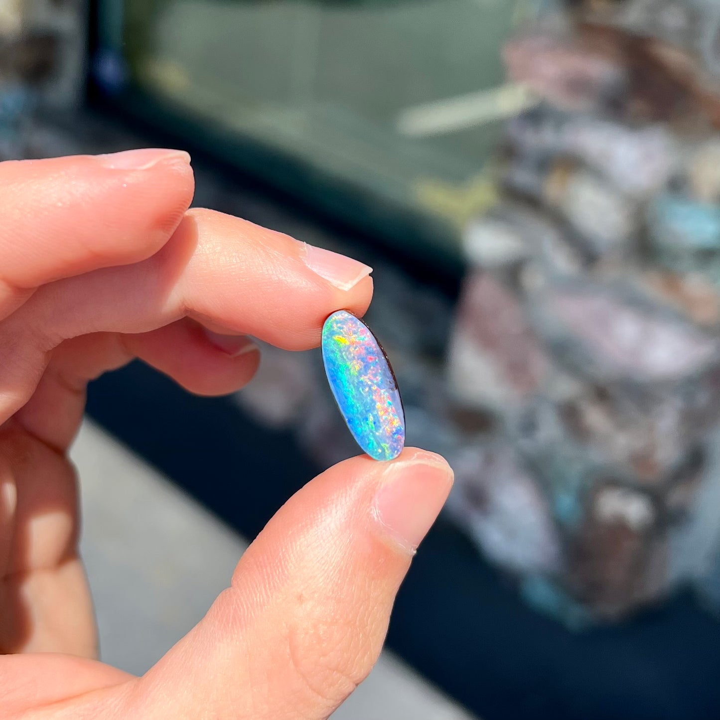 A loose, oval cut rainbow boulder opal gemstone.