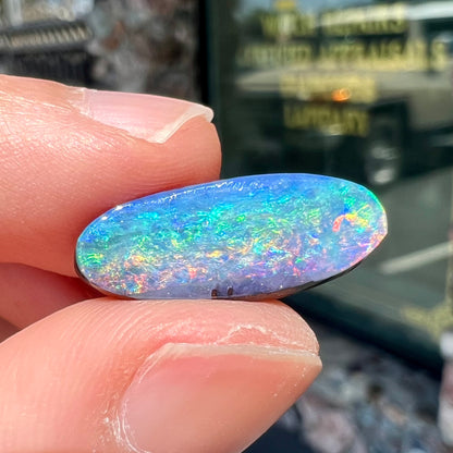 A loose, oval cut rainbow boulder opal gemstone.