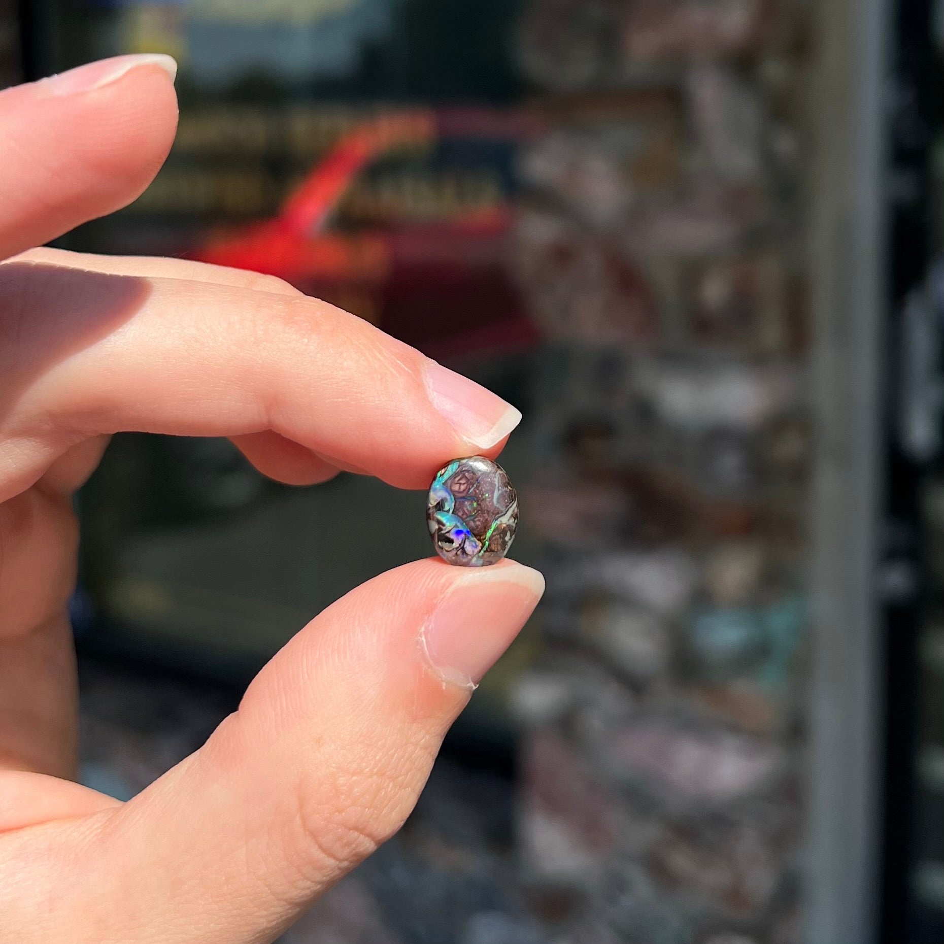 A loose, oval cabochon cut boulder opal stone from Koroit, Australia.  The opal has a bright green flash.