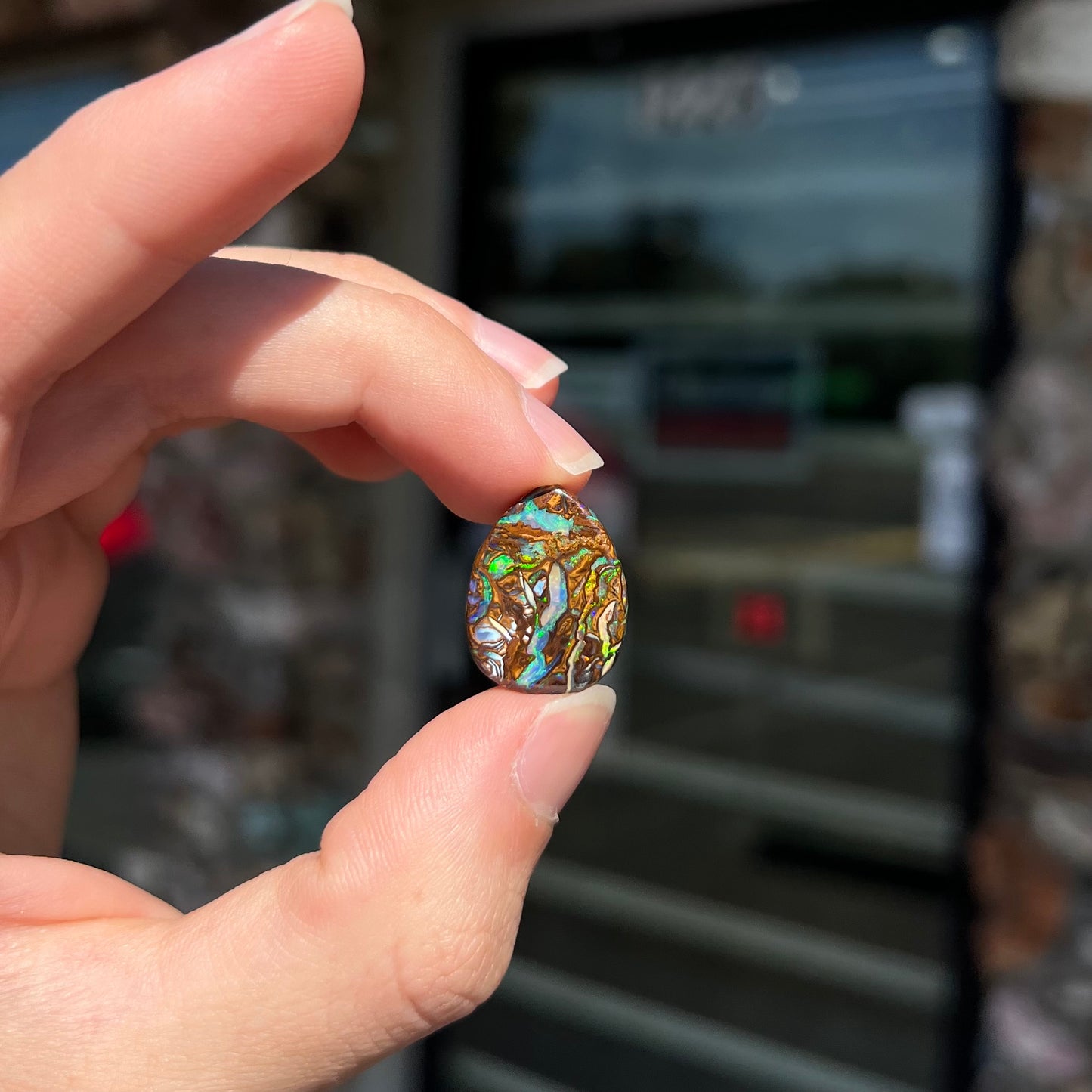 A loose, pear shaped boulder opal stone from Koroit, Australia that has vivd green and blue veins of color.