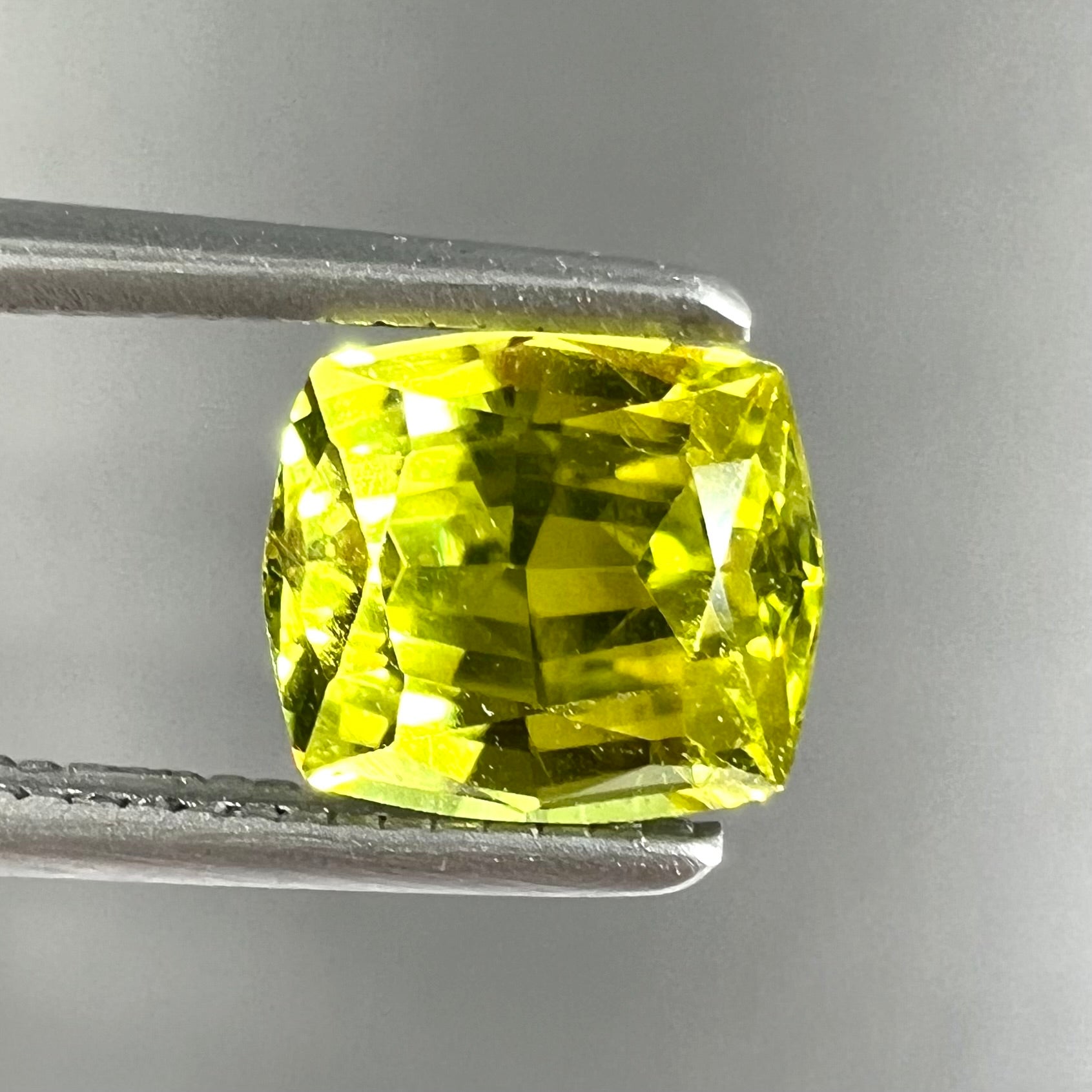 A loose, modified cushion cut greenish yellow chrysoberyl gemstone.