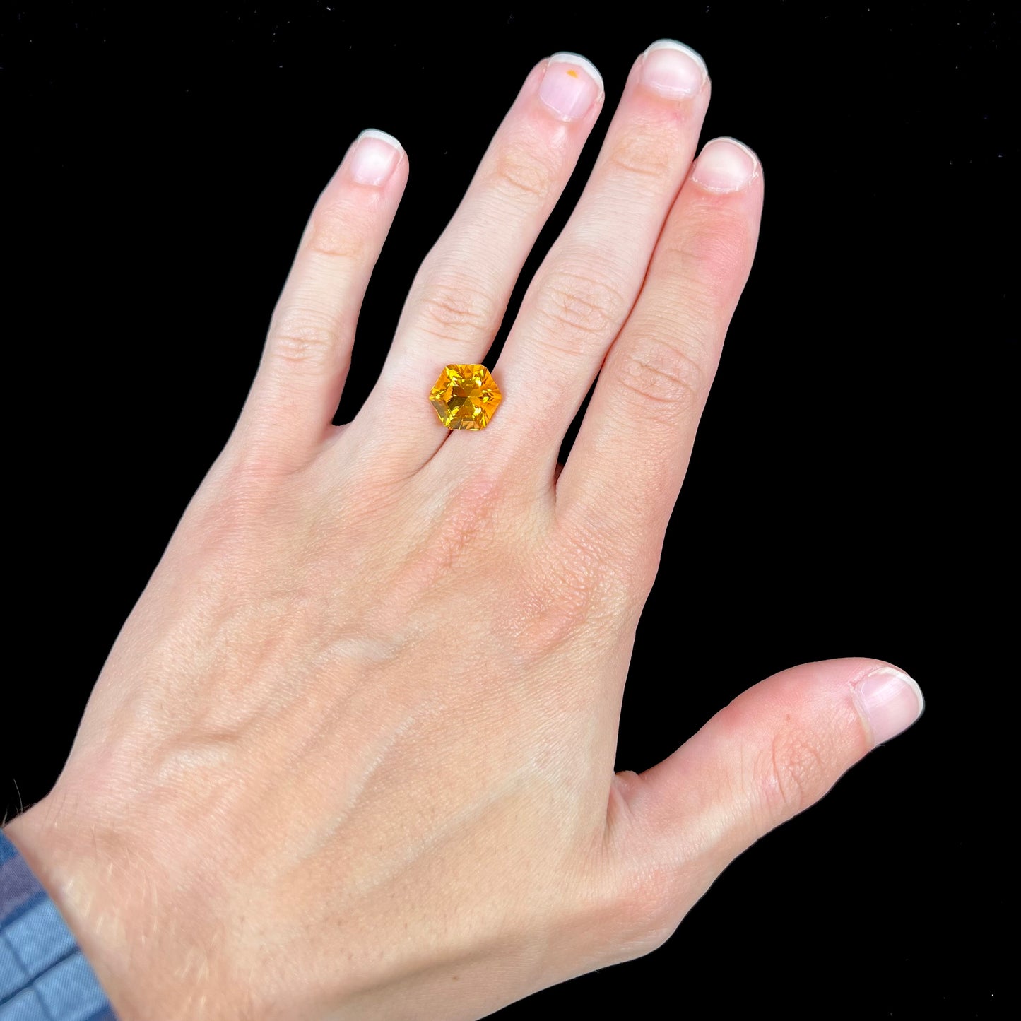 A loose, faceted hexagon cut citrine gem.  The stone is golden yellow color.