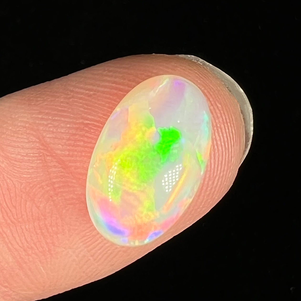 An oval cabochon cut crystal opal gemstone from Coober Pedy, Australia.