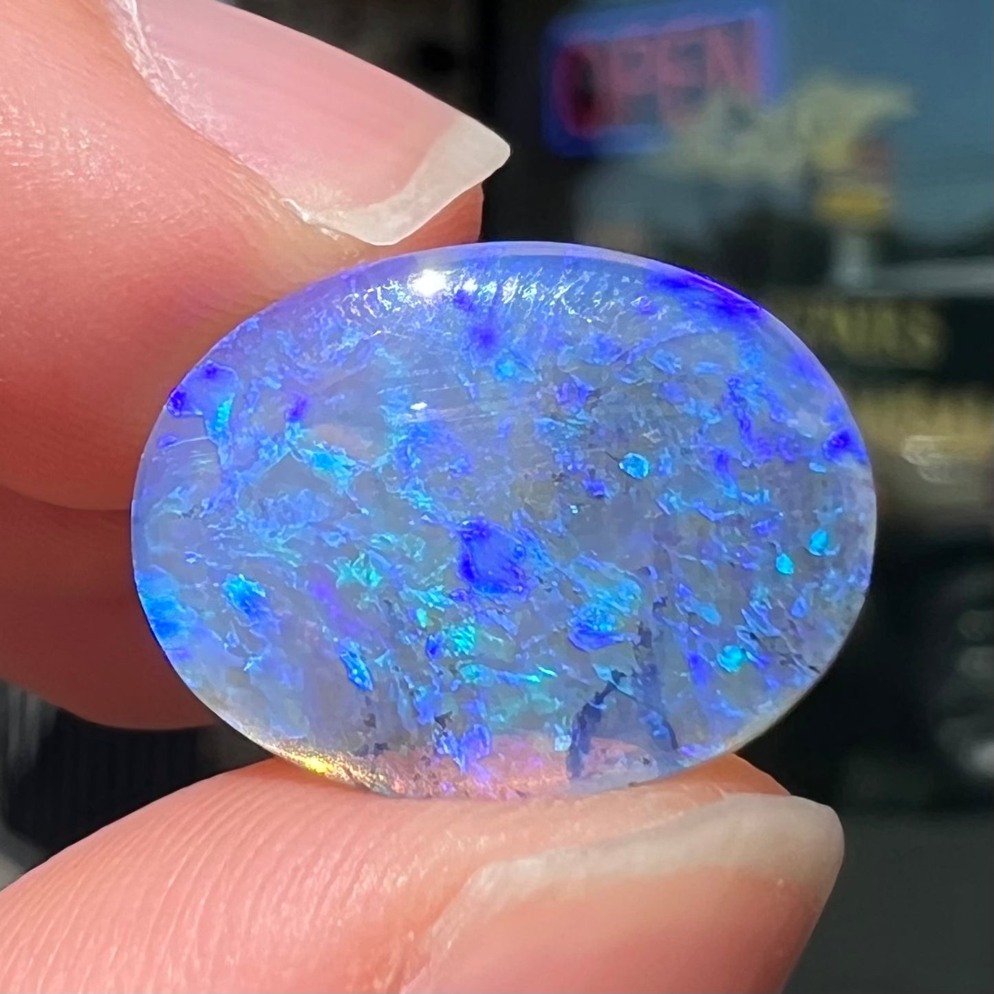 A loose, oval cabochon cut crystal opal from Lightning Ridge, Austalia that weighs 5.16 carats.  The stone has blue and purple colors.