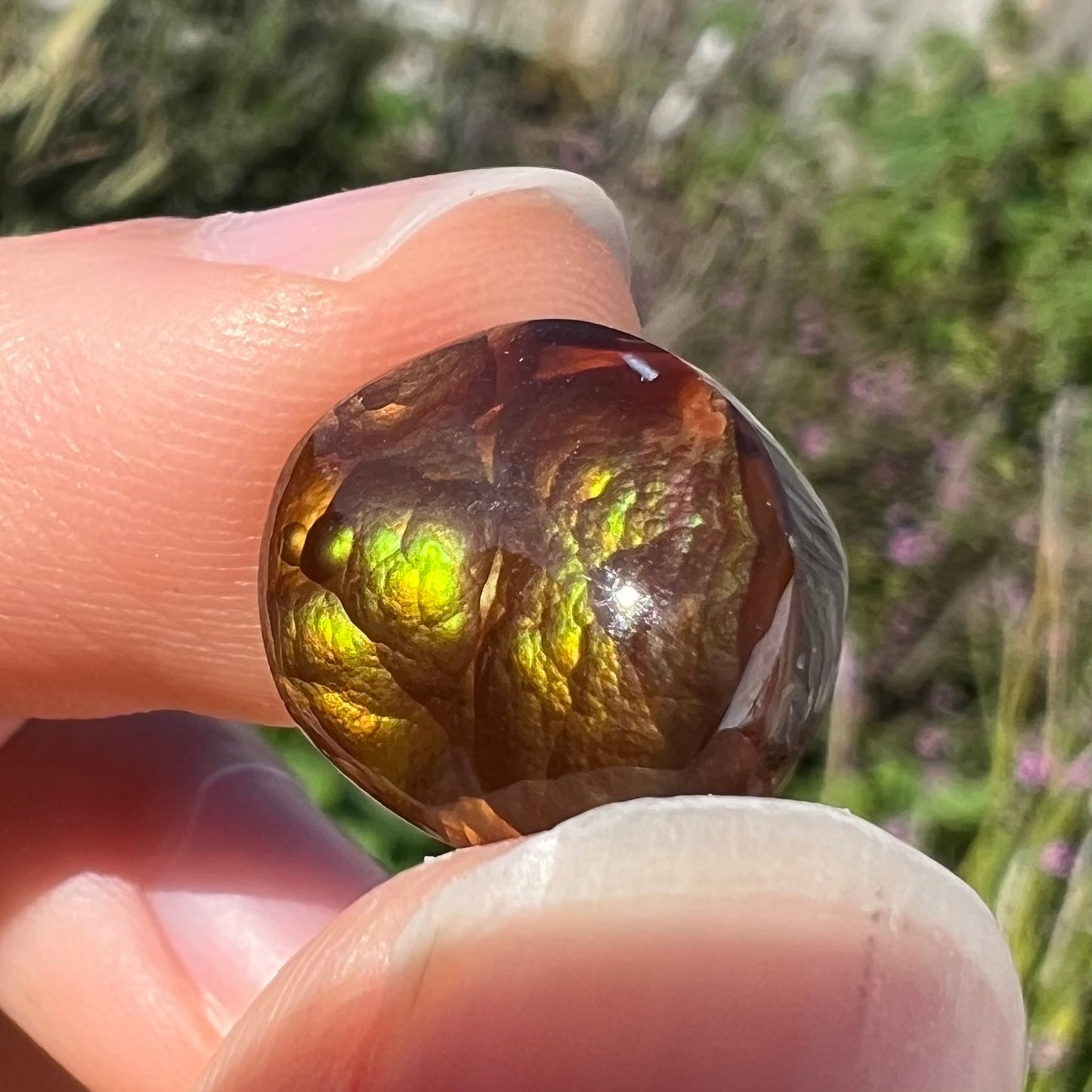 A loose, round Mexican fire agate stone.  The stone shines colors of green, yellow, and orange.