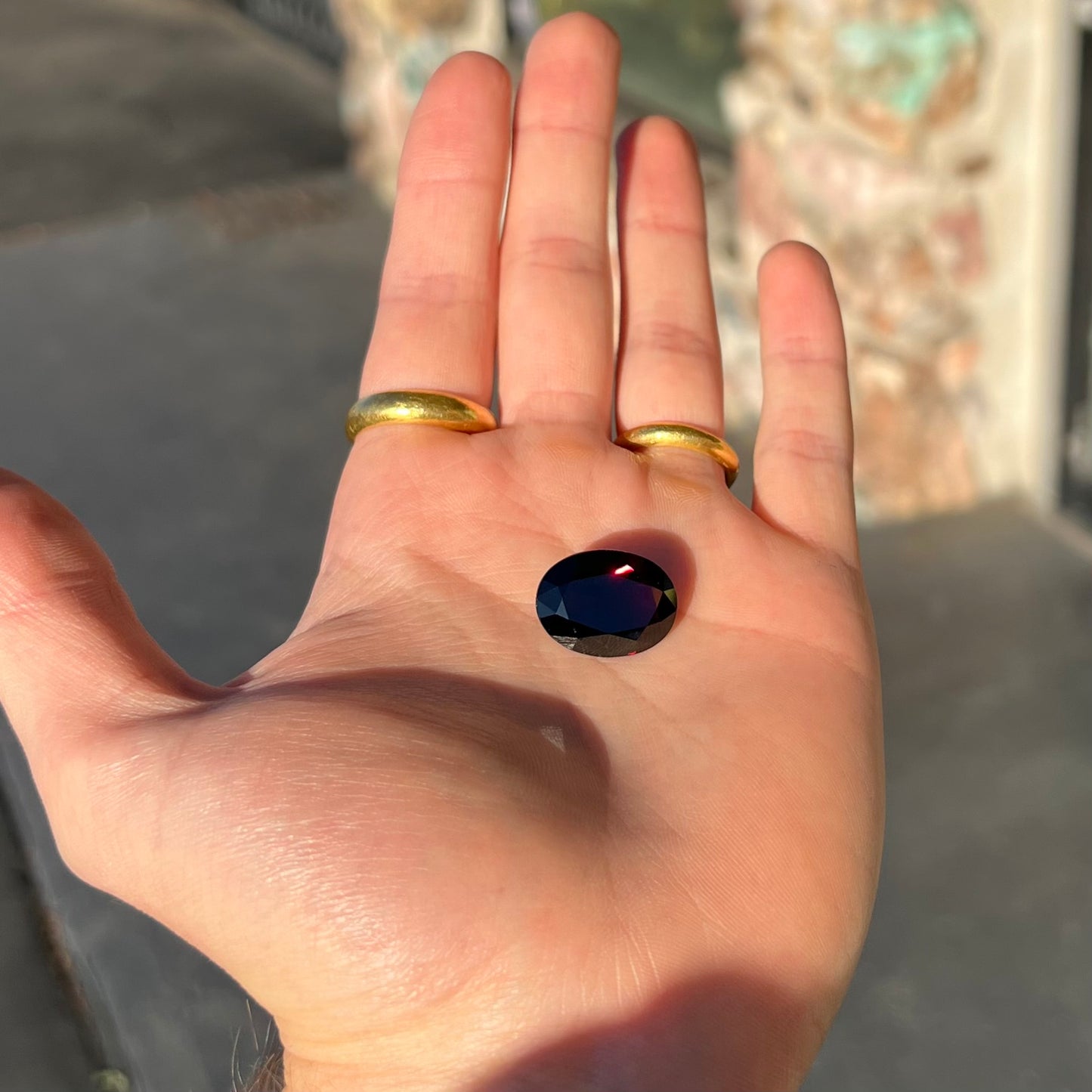 A loose, faceted oval cut pyrope garnet gemstone.  The stone is a deep, dark red color.