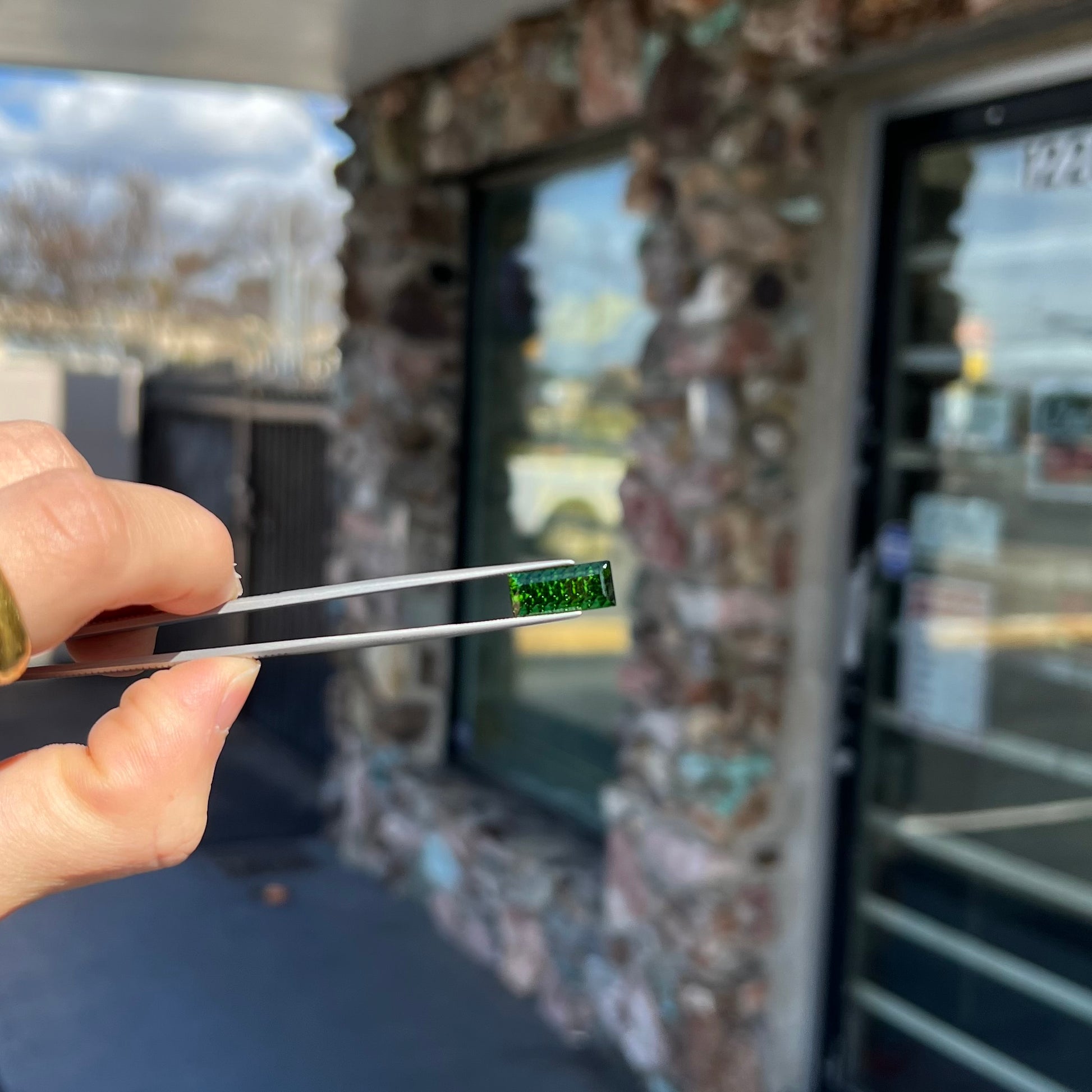 A loose, rectangular laser cut green tourmaline gemstone.