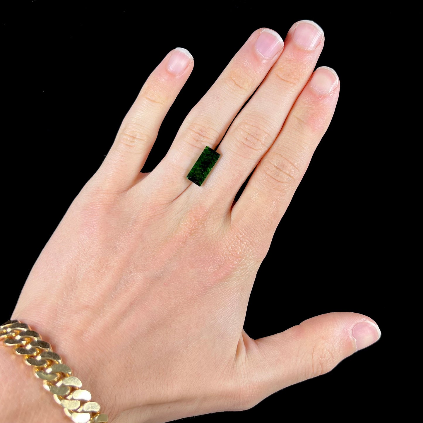 A loose, rectangular laser cut green tourmaline gemstone.