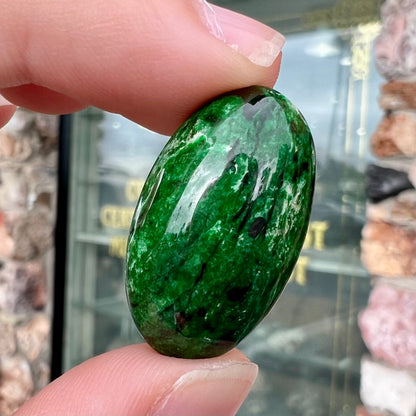 A loose, oval cabochon cut green maw sit sit stone.