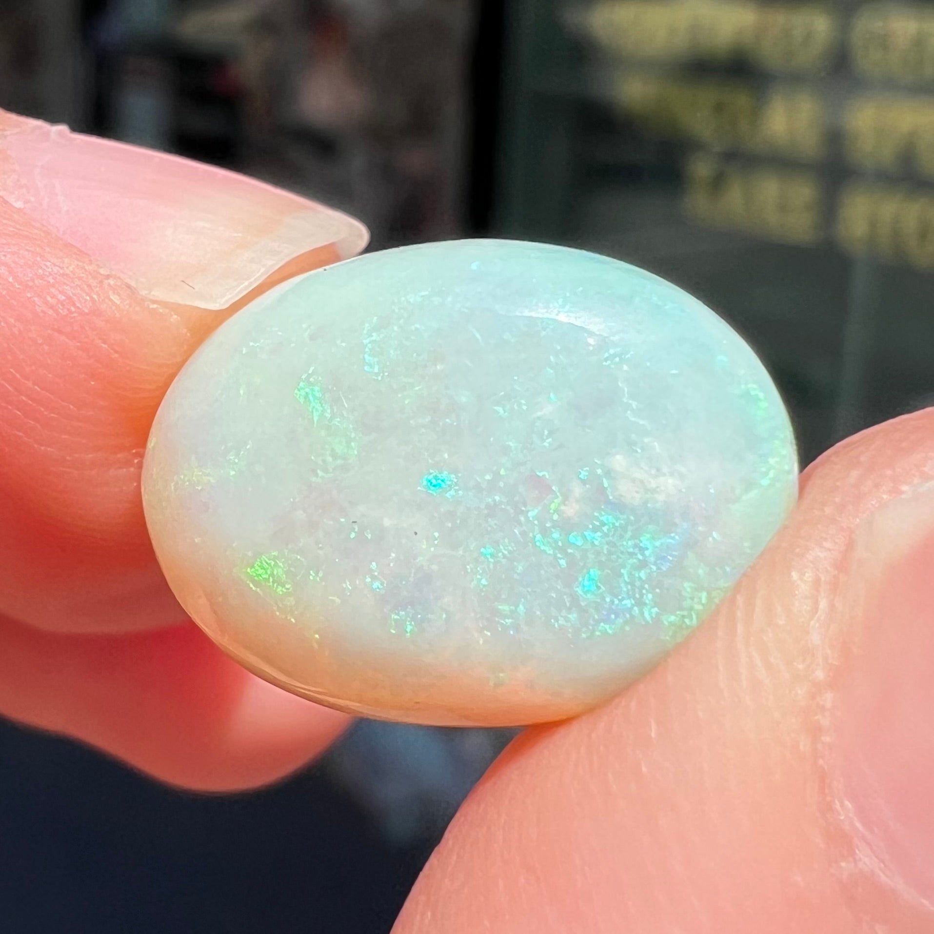 An oval cabochon cut white opal stone from Coober Pedy, Australia.  The opal has subtle colors of green and blue.