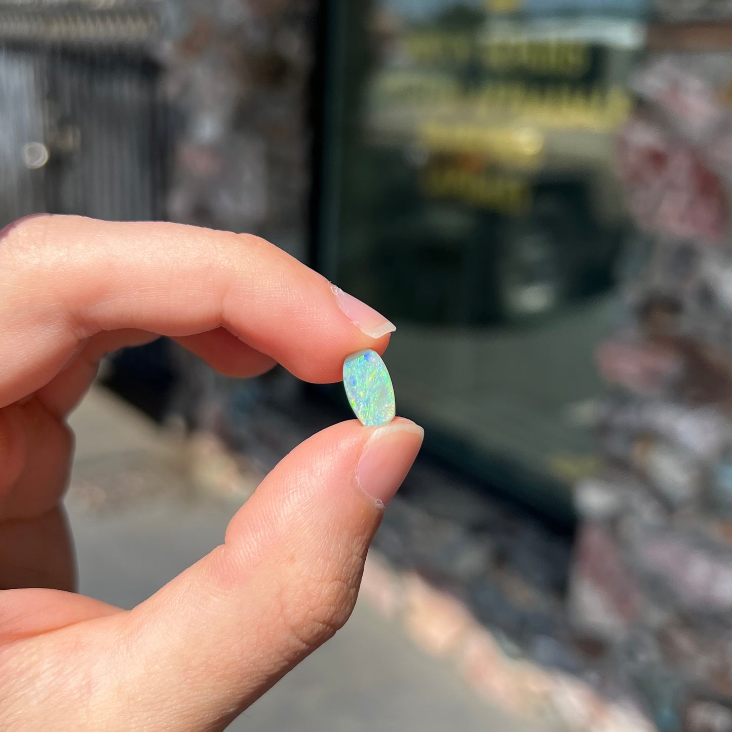 A loose, barrel shaped semi-black opal stone from Lightning Ridge, Australia.  The stone plays green colors.