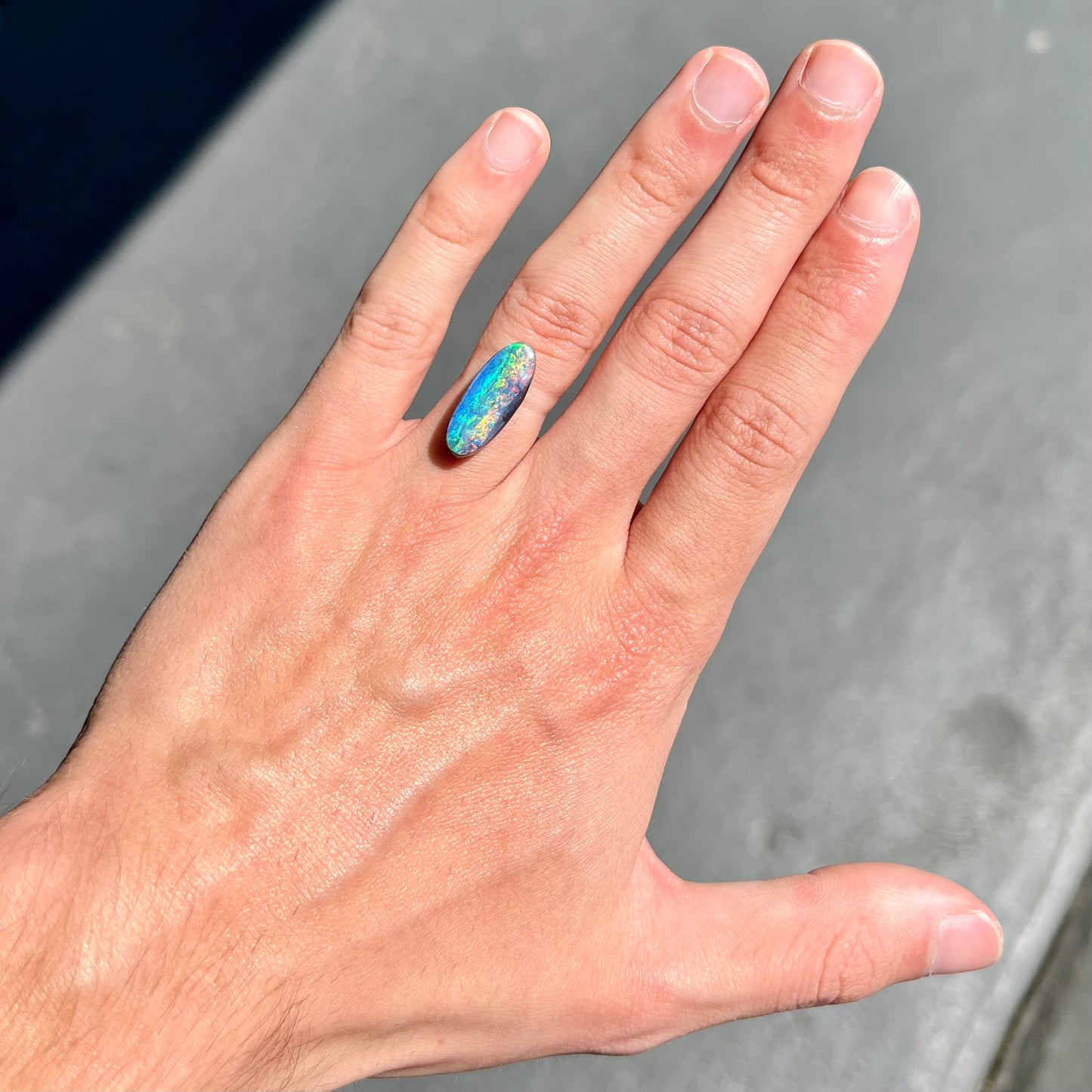 A loose, oval cut rainbow boulder opal gemstone.