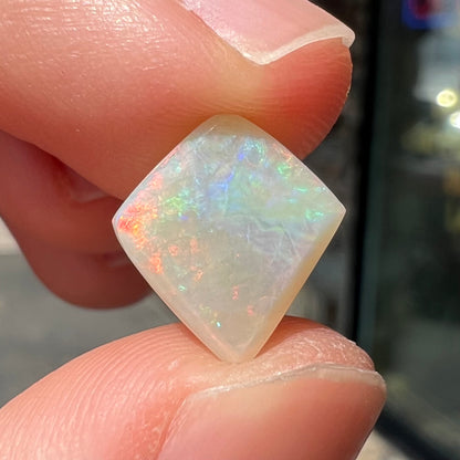 A loose, kite shaped white opal stone from Coober Pedy, Australia.  The stone has subdued red colors.