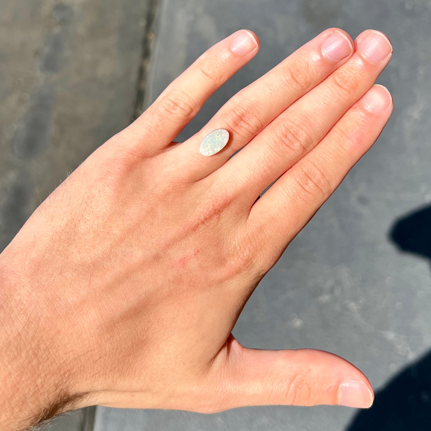 A loose, oval cabochon cut white opal stone from Coober Pedy, Australia.