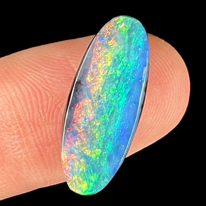 A loose, oval cut rainbow boulder opal gemstone.