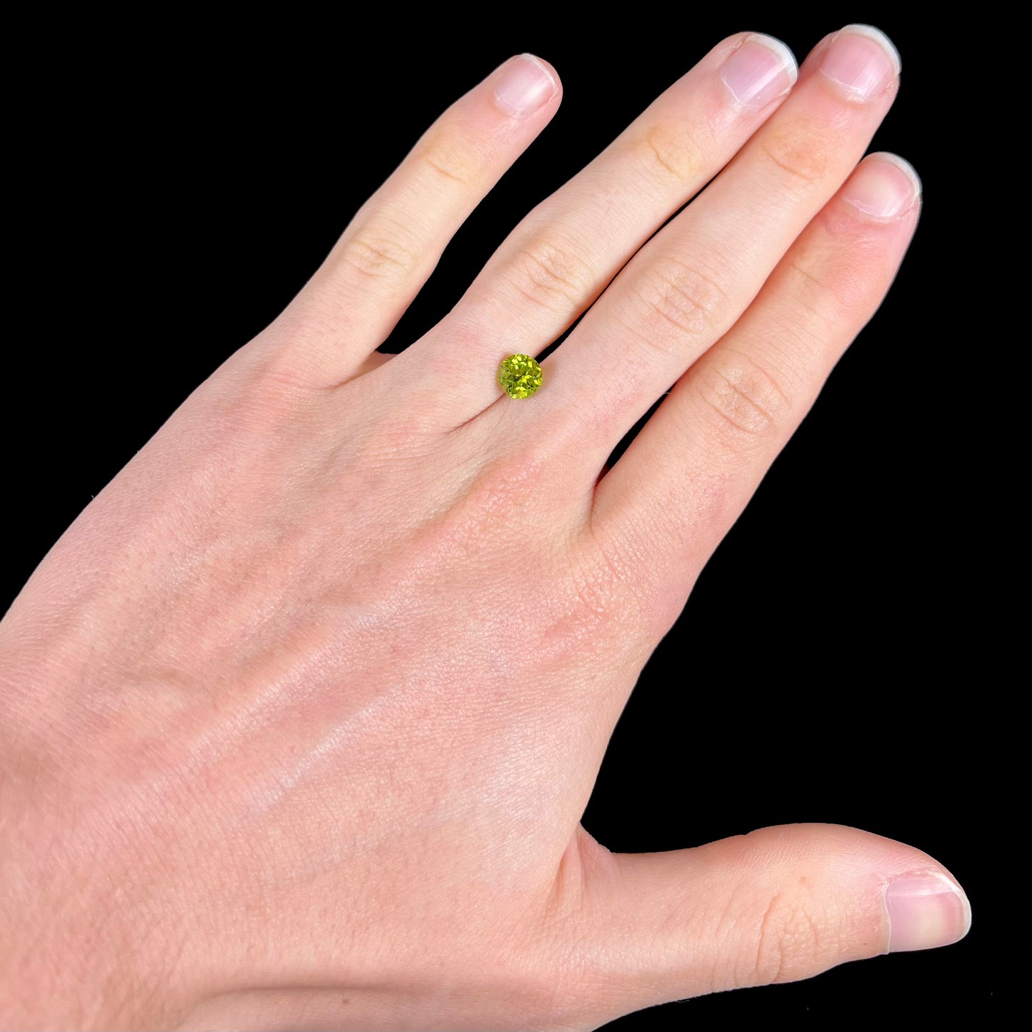 A loose, round brilliant cut peridot gemstone.