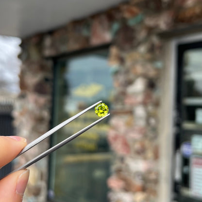 A loose, round brilliant cut peridot gemstone.