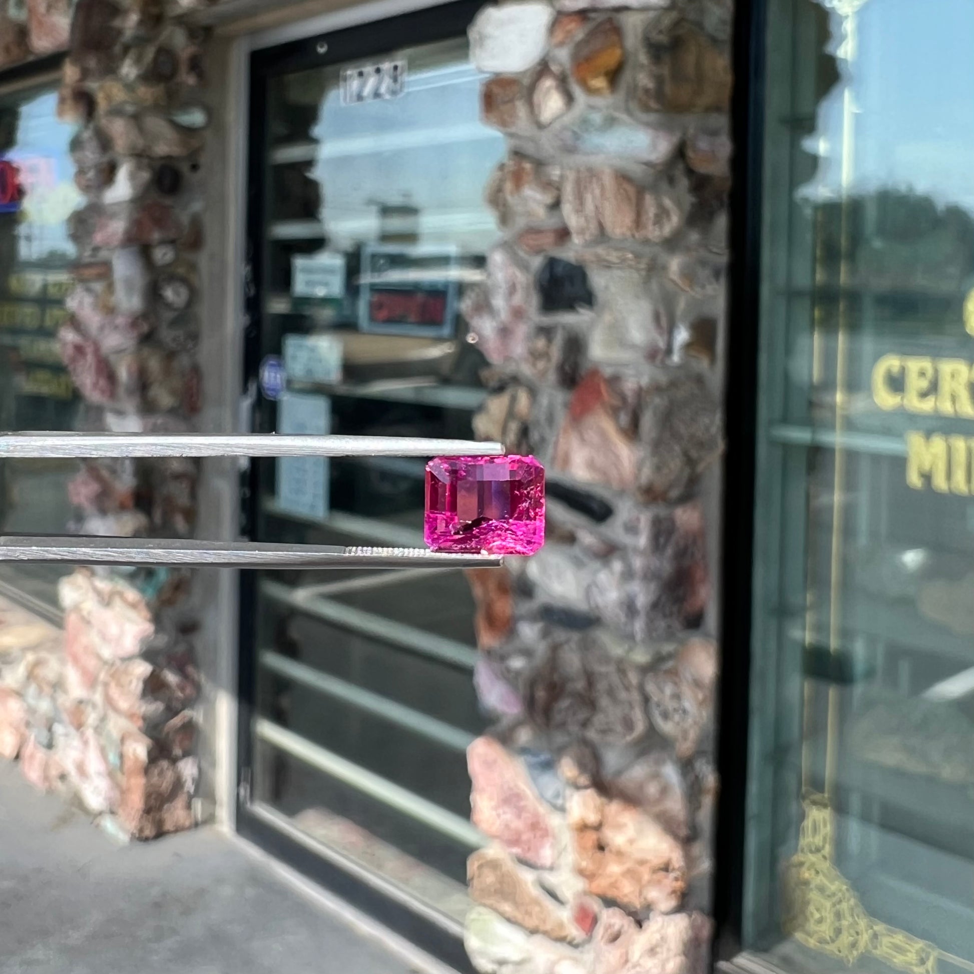 A loose, faceted modified emerald cut hot pink tourmaline stone.