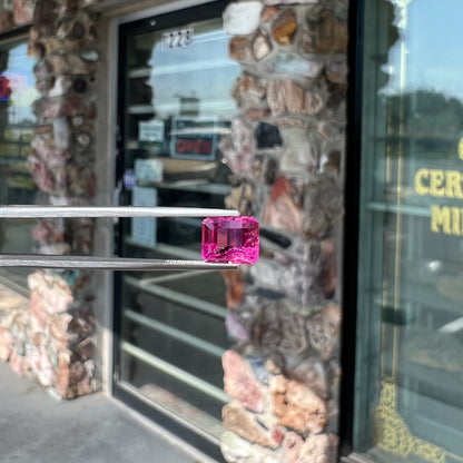 A loose, faceted modified emerald cut hot pink tourmaline stone.