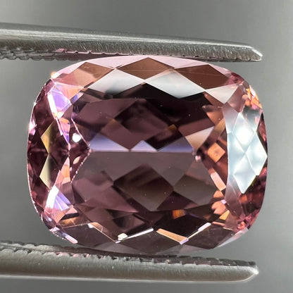 A loose, cushion cut light pink tourmaline gemstone.