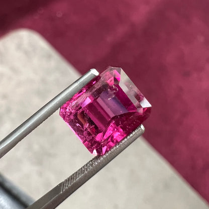 A loose, faceted modified emerald cut hot pink tourmaline stone.