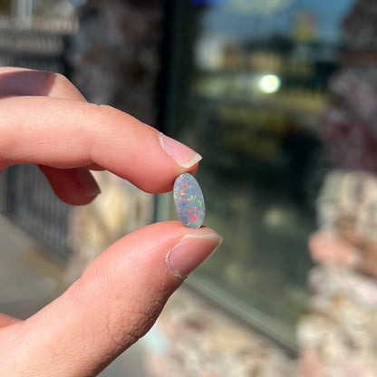 A loose, 3.01 carat, oval cut semi-black opal stone from Lightning Ridge, Australia.  The opal has red colors.